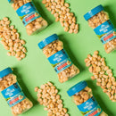 Five jars of Mauna Loa macadamia nuts are arranged on a bright green background, with scattered nuts surrounding the jars, showcasing their packaging and product details.